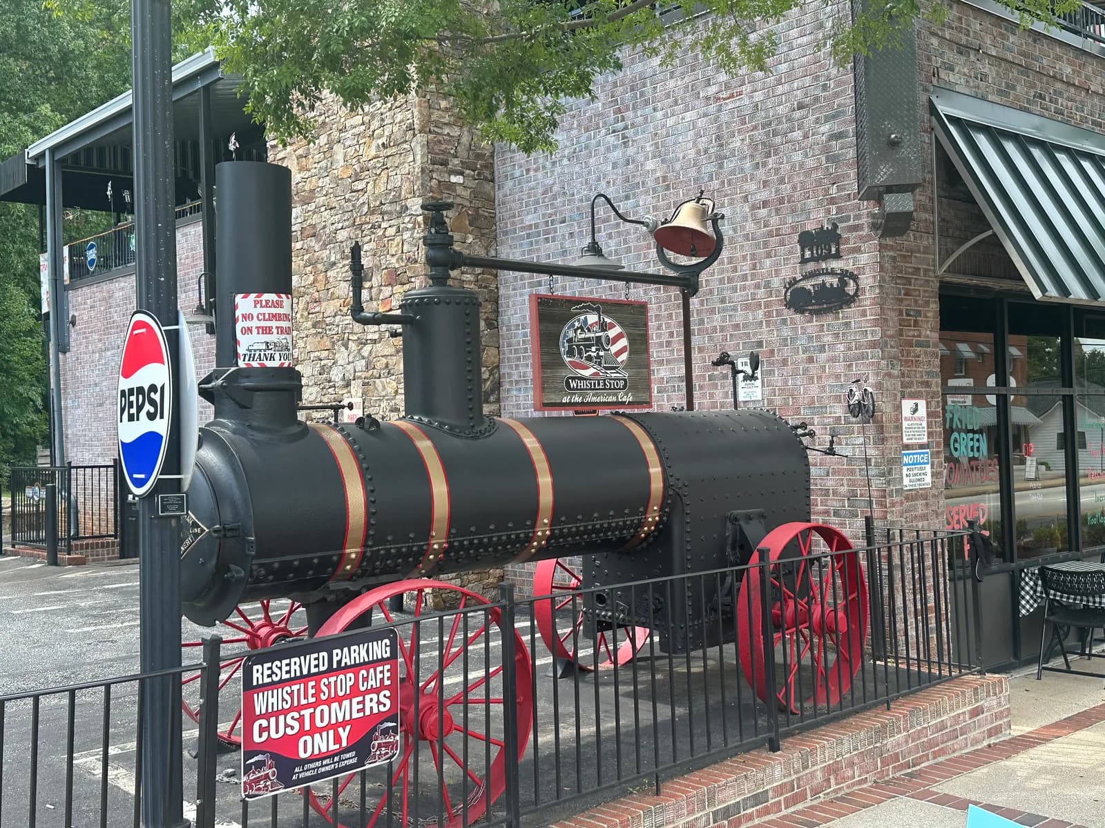 The black locomotive replica with red wheels parked outside the Whistle Stop at the American Cafe in downtown Travelers Rest, South Carolina