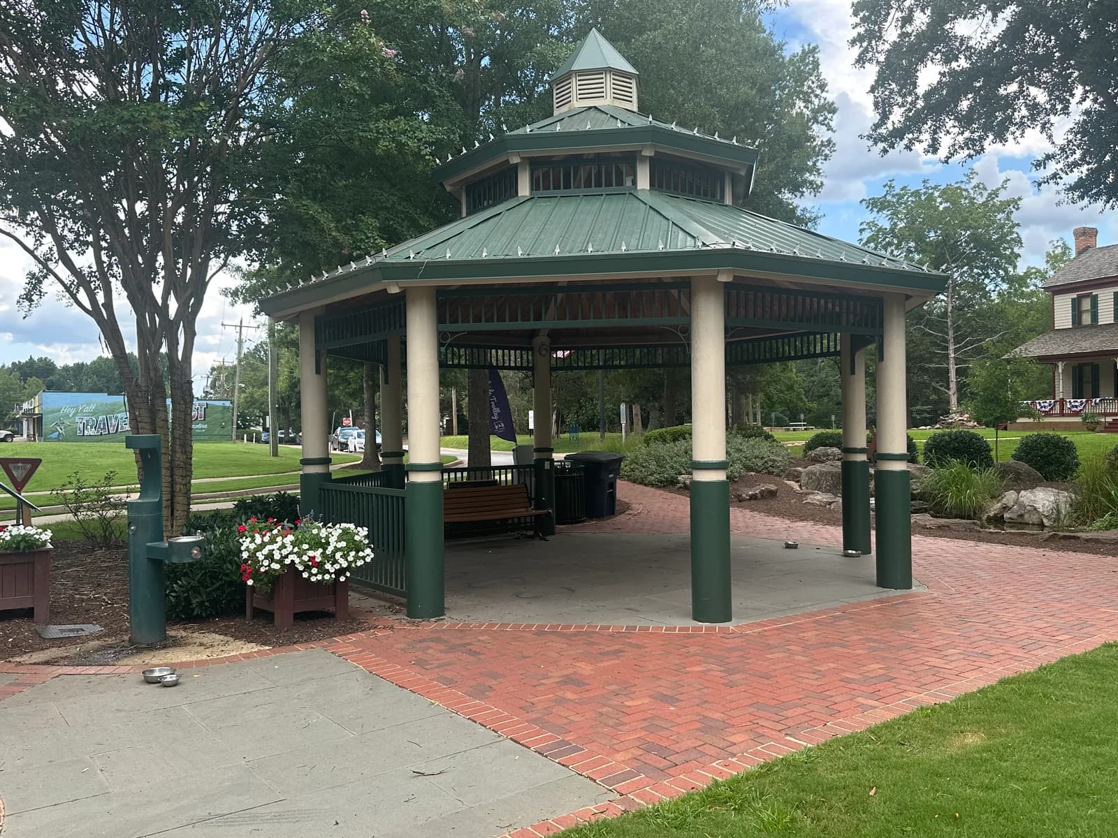 A covered pavilion with a green roof and brick walkway in a park in Travelers Rest, South Carolina