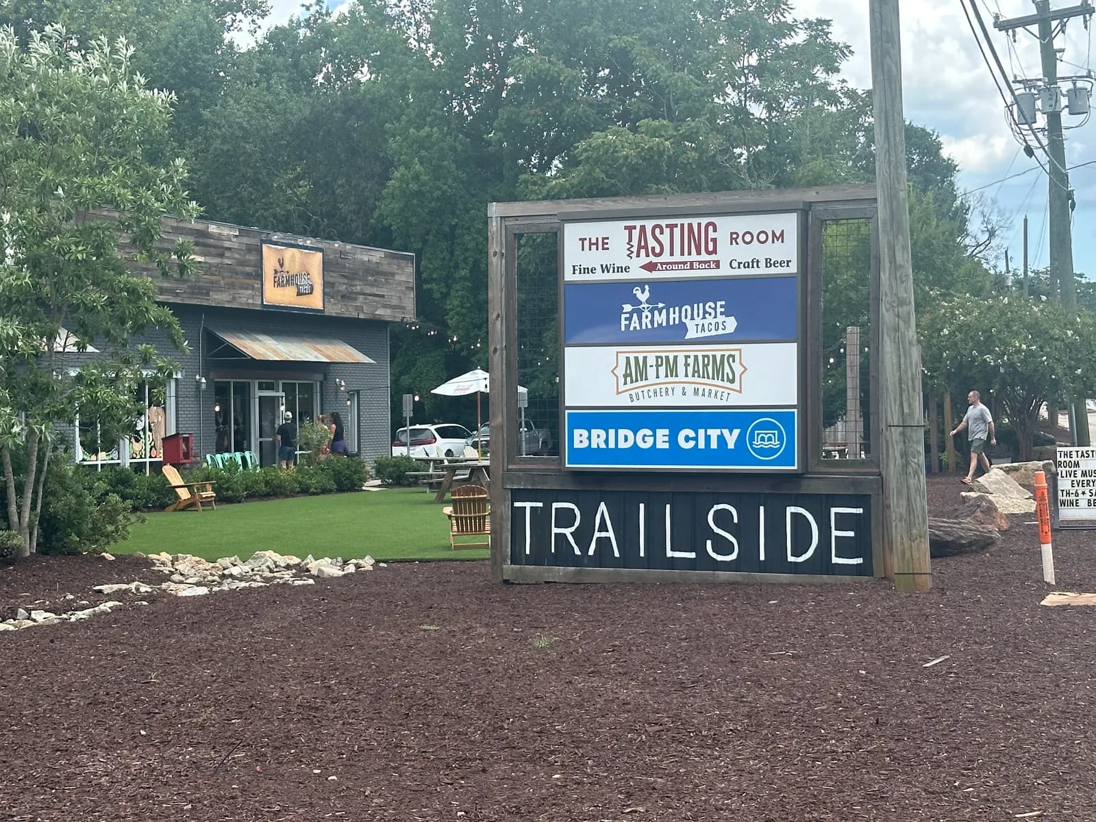The Trailside sign in Travelers Rest, South Carolina, listing The Tasting Room, Farmhouse Tacos, AM-PM Farms Butchery and Market, and Bridge City
