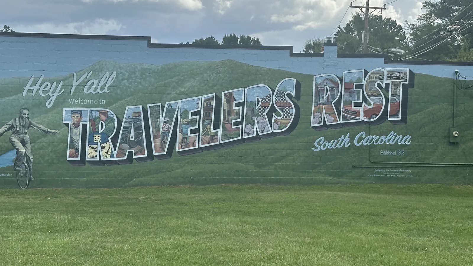 The Hey Y'all Welcome to Travelers Rest, South Carolina mural, painted with the Blue Ridge foothills and Established 1808, on a building in downtown Travelers Rest
