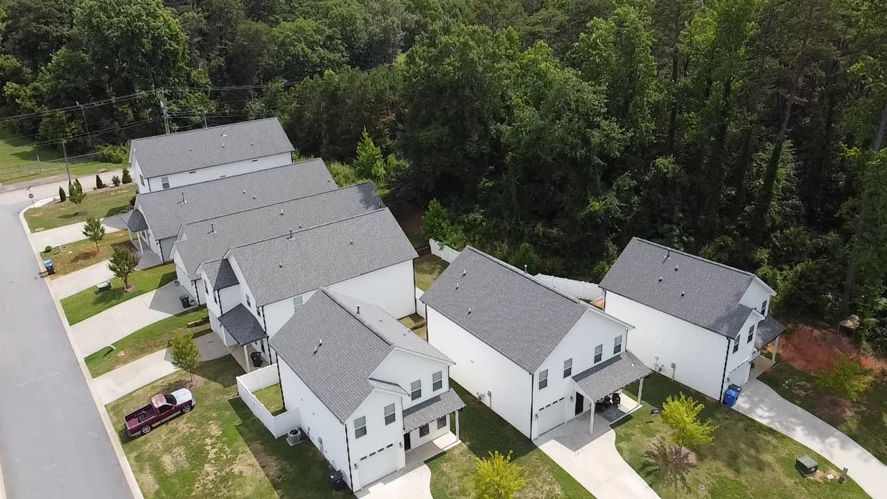 Aerial view of a row of new two story single family rental homes backing onto woods at Village West in Travelers Rest, South Carolina